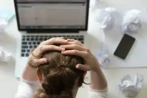 retrato mujer agarrando la cabeza escritorio cerca del portatil