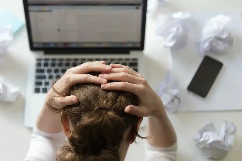 retrato mujer agarrando la cabeza escritorio cerca del portatil