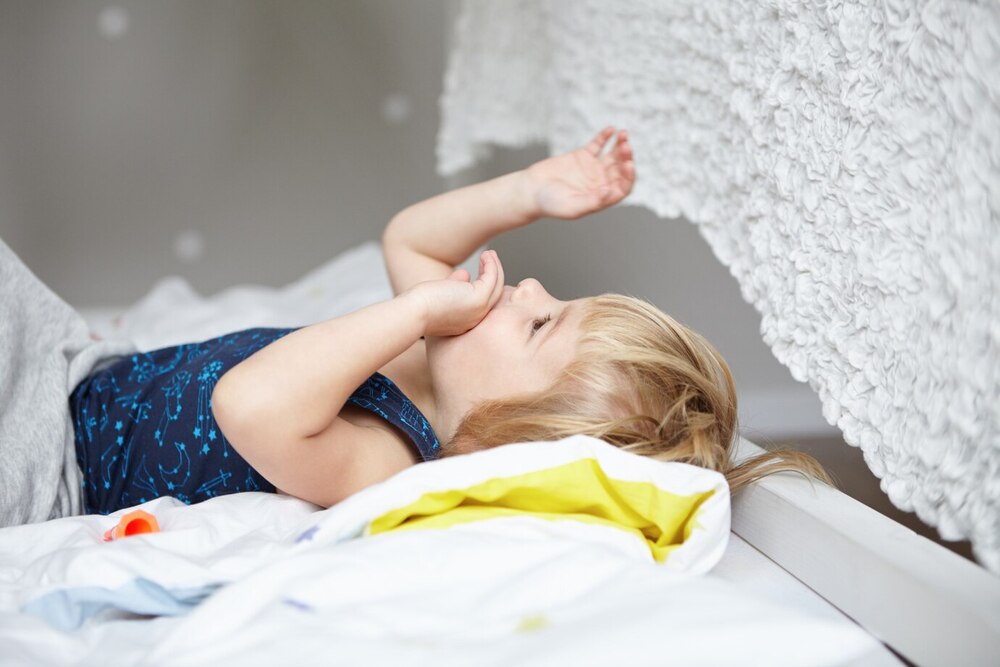 concepto infancia feliz niño lindo cabello rubio acostado cama-su acogedor dormitorio-blanco jugando sus manos