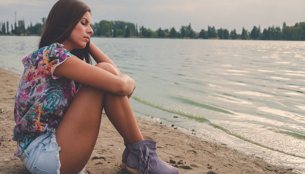 Chica en la playa preocupada por el verano y la salud mental